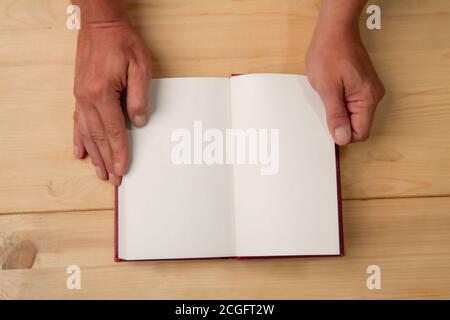 Male hands opened the page of a new book on a wooden background Stock Photo