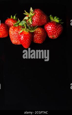 A few ripe strawberries lie on a black background. Place for a copy of space Stock Photo