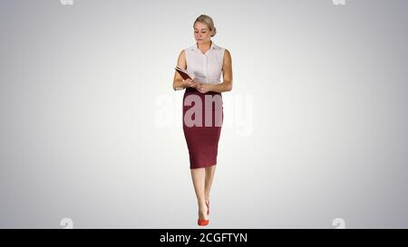 Successful businesswoman or entrepreneur taking a look in her notes on gradient background. Stock Photo