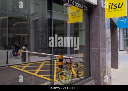 As workers in London largely remain working from home during the Coronavirus pandemic, the reflection of a locked bike, a traffic grid and street barrier in the City of London, on 4th September 2020, in London, England. Stock Photo