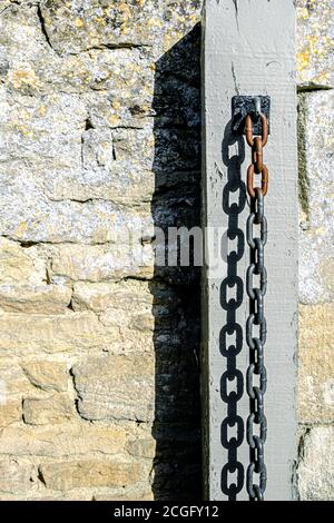 A thick metal chain hanging from a gate post whre it has been left after a security padlock has been undone. Stock Photo