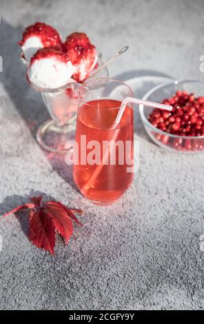 Morse of red cranberries and ice cream with jam in a glass bowl, red autumn leaves on the table . A place for the space mine. Vertical orientation Stock Photo