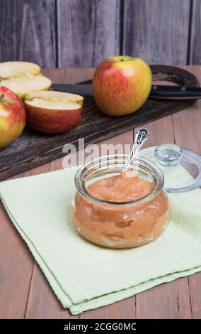 A can of Apple puree and sliced fresh apples on a wooden chopping Board on a wooden background . Vertical orientation. Stock Photo