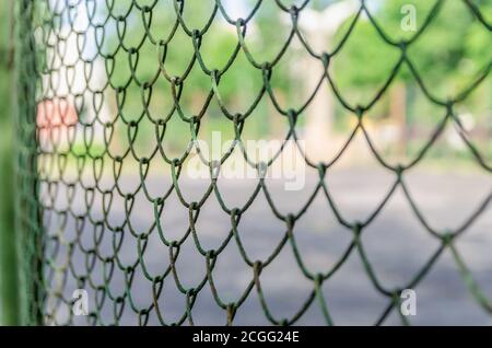 Old metal fence chain links on green background, metal mesh Stock Photo