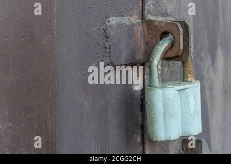 Large gray barn lock on a dark iron wall, gate. Natural. Closed door. Old metal lock Stock Photo