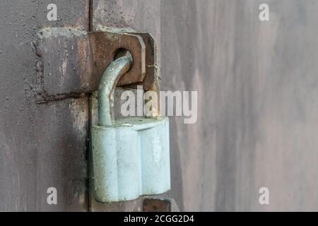 Large gray barn lock on a dark iron wall, gate. Natural. Closed door. Old metal lock Stock Photo