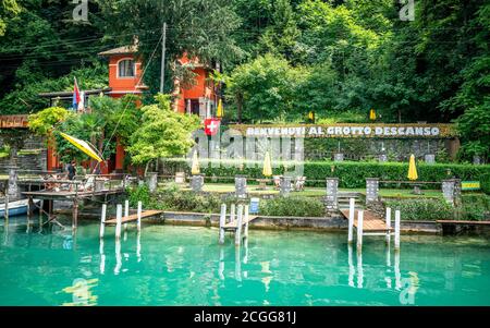 Gandria Switzerland , 1 July 2020 : Pier and people in middle of green nature and Grotto Descanso restaurant sign at Cantine di Gandria Switzerland Stock Photo