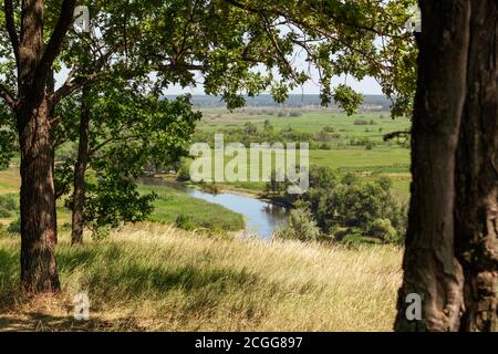 Summer view on river valley in distance from hill through green trees and dry grass. Zmiyevsky cliffs on Siverskyi Donets River in Ukraine Stock Photo