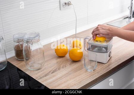 Woman squeezing oranges in the kitchen Stock Photo