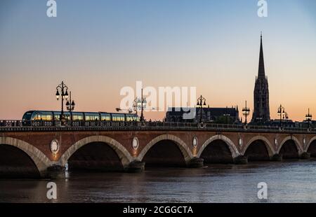 Street lights lit up at sunset, tram crossing Pont de Pierre bridge  in the background, Bordeaux, France. Stock Photo