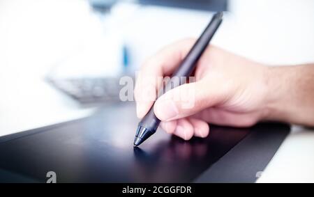 Electronic Signature Technology. Man hand with stylus pen on digital tablet with computer and modern office background, close up. Business signing con Stock Photo