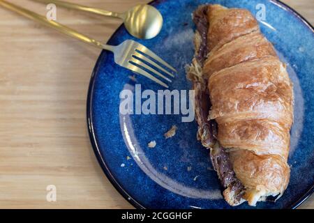 Fresh croissants with chocolate on a blue plate on wooden tray Stock Photo