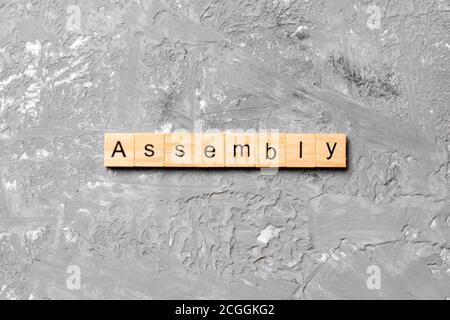 ASSEMBLY word written on wood block. ASSEMBLY text on cement table for ...