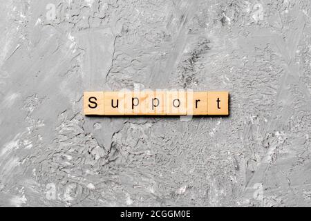 Support word written on wood block. Support text on cement table for your desing, concept. Stock Photo