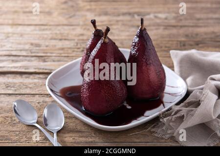 Poached pears in red wine on wooden table Stock Photo