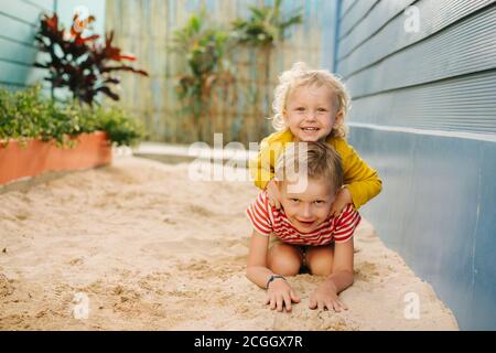 Outdoor portrait of big brother and his little sister against blue house wall Stock Photo