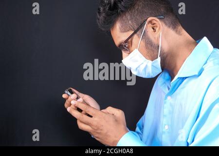 young man with face mask using smart phone indoor  Stock Photo