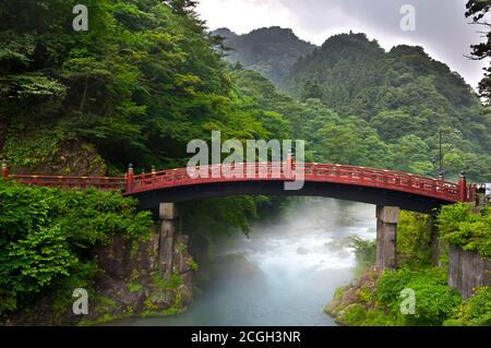 Red sacred bridge Shinkyo in Nikko, Japan and a mist rising from the river Stock Photo