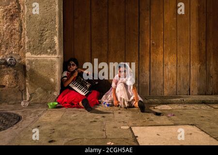 Mexican girls, dressed as La Catrina, sit on the street during the Day of the Dead celebrations in Oaxaca, Mexico. Stock Photo