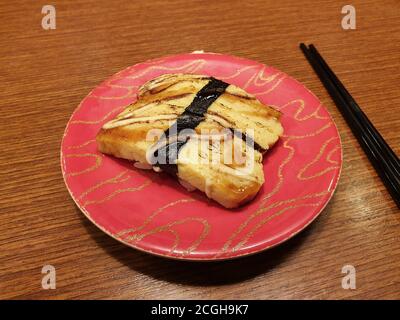 Tamago Sushi - Tamagoyaki, a thin egg omelet on a base of sushi rice. Tied together with a seaweed strip. Recommended for vegetarian sushi fans. Stock Photo