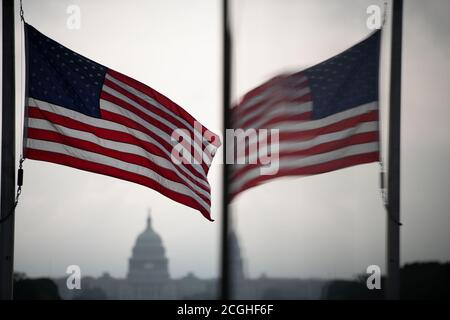 Washington, USA. 11th Sep, 2020. An American flag flies at half staff and is reflected in a window with the U.S. Capitol Building seen behind, near the Washington Monument in Washington, DC, on September 11, 2020, amid the coronavirus pandemic. On the 19th anniversary of 9/11, Democratic Candidate for President Joe Biden visited the site of the attacks in New York City for a commemoration before heading to the Shanksville, PA, memorial where President Trump will also visit - across the country flags were flown at half staff. (Graeme Sloan/Sipa USA) Credit: Sipa USA/Alamy Live News Stock Photo