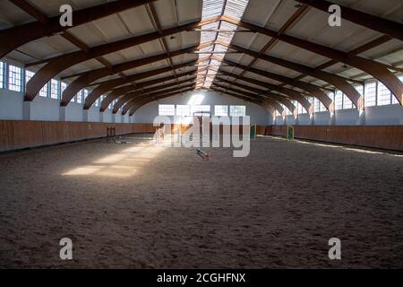 A light-flooded riding arena with some jumping obstacles. Stock Photo