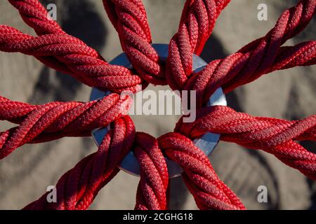 Texture close up of a seat made of ropes. Red braided ropes held in the middle by a metal ring. Stock Photo