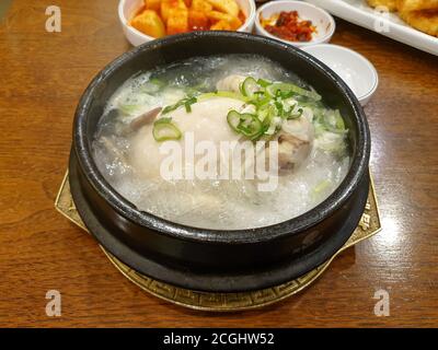 Samgye-tang, or ginseng chicken soup. Korean traditional soup for body health. Whole young chicken filled with garlic, rice, jujube, and ginseng. Stock Photo