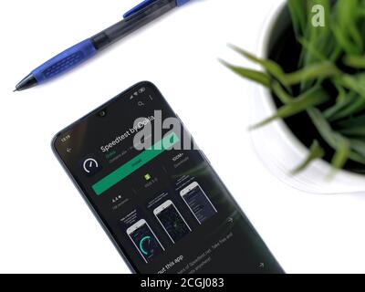 Lod, Israel - July 8, 2020: Modern minimalist office workspace with black mobile smartphone with Speedtest app play store page on white background. To Stock Photo