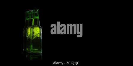 Green beer bottles on a black background on the side. Free space for text. Stock Photo