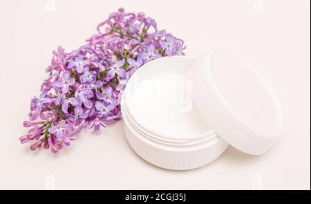Cream in a jar on a white background and lilac flowers. Skin care, health care, spa Stock Photo