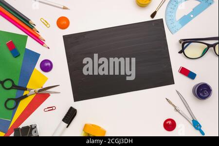 Office supplies in the form of a frame, space for text on a black school Board, white background, top view. Stock Photo