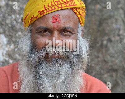 Old Nepali beggar and Hindu devotee with red rice tilak mark on his forehead smiles for the camera. Stock Photo