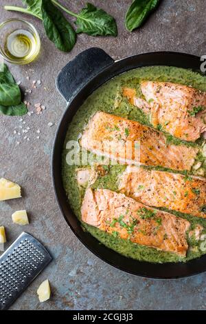 Grilled Salmon with spinach and garlic cream sauce in a frying pan, top view Stock Photo