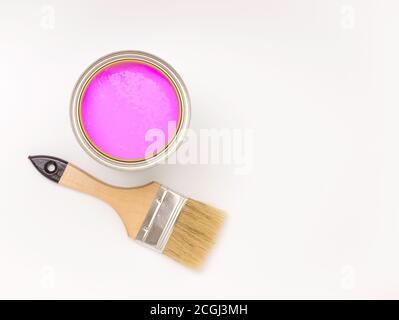 Tools for construction and decoration. Paintbrush next to a can of pink paint on a white background, top view, free space for text. Stock Photo