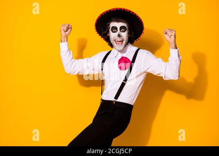 Photo portrait of cheerful crazy nice handsome funny mexican guy in traditional costume raising fists up isolated bright color yellow background Stock Photo