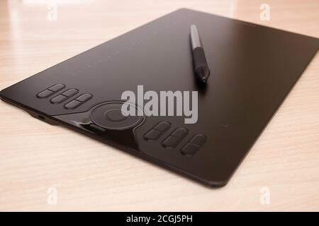 Graphic tablet and stylus with stylus stand on the table. Side view, tools for graphic drawing. Stock Photo