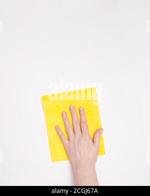 Part of the hand with a yellow cloth for dusting and removing dirt. Cleaning, white background, free space for text. Stock Photo