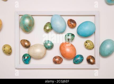 Colored Easter eggs in a wooden white frame on a white background. Stock Photo