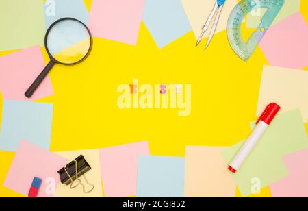 The word EASY in the center on a yellow background, colored letters. Frame of empty note papers and stationery. Top view. Stock Photo