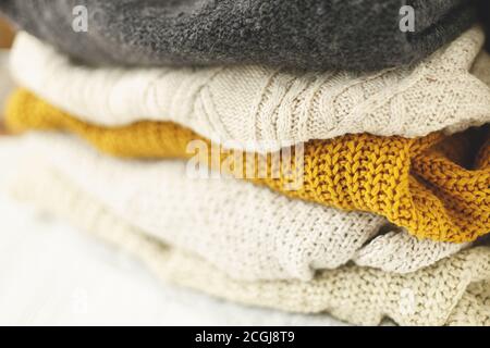 Cozy knitted sweater stack for cold autumn weather on white background. Stylish white, yellow and grey sweaters close up with space for text. Hello fa Stock Photo