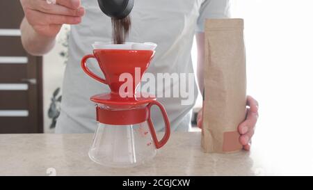 A man pours freshly ground coffee from a bag into a dropper for preparation v60. A professional set for making a pourover at home Stock Photo
