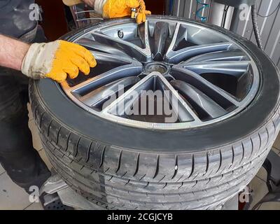 Seasonal tire service. Professional mechanic in a car service. A car wheel on a machine for replacing tires. A mechanic at work. Stock Photo