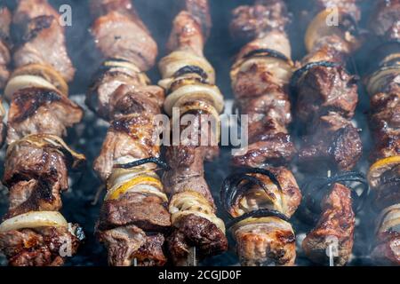 Pork shish kebab roasting on a brazier strung on a skewer, top view Stock Photo