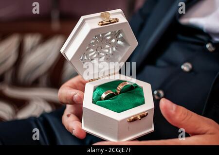 the groom holds wedding rings in a white box Stock Photo