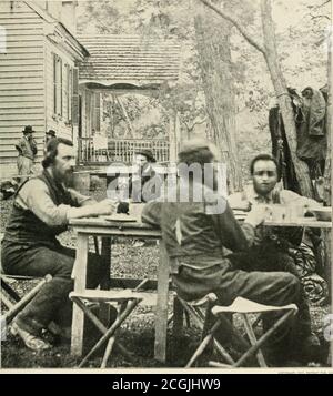 . The photographic history of the Civil War : thousands of scenes photographed 1861-65, with text by many special authorities . COPYRIGHT, , PATRIOT PUB. CO. IN THE HEART OF THE HOSTILE COUNTRY—MAY, 1862 As the secret-service men sit at Follens house, near Cumberland Landing, all is ready for the advance to the Chickahominy and toRichmond. The scouts and guides are aware that there is hard and dangerous work before them. Their skilful leader, whom theyknow as Major Allen, sits apart from the group at the table, smoking his pipe and thinking hard. He must send his men into theConfederate lines Stock Photo