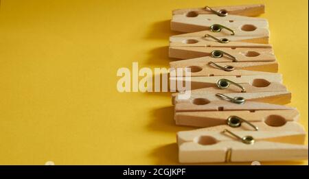 Pattern of wooden clothespins on a yellow background close-up. Banner Stock Photo