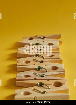 Pattern of wooden clothespins on a yellow background close-up. Vertical format Stock Photo