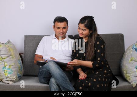 Young Indian couple discussing with documents on sofa. Stock Photo
