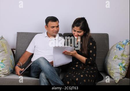 Young Indian couple discussing with documents on sofa. Stock Photo